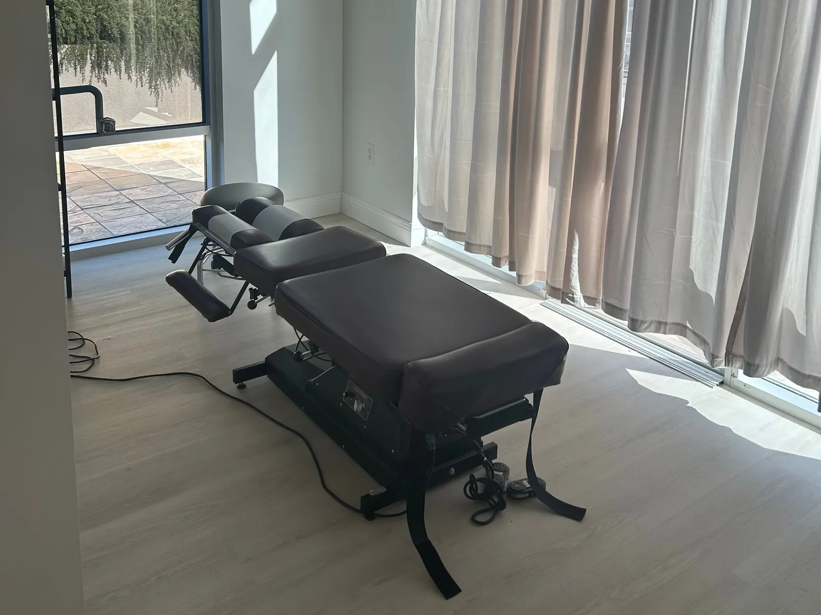 An adjusting table by the windows in a treatment room at The Function Chiropractic in Palo Alto
